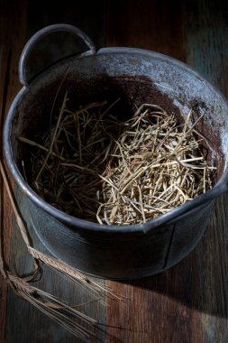 Tahta zeminde saman olan eski bir leğen.