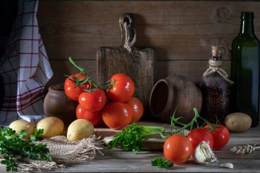 Kırsal bir masada, tahta bir duvarın karşısında taze sebzeler. Domates, patates, maydanoz, sarımsak