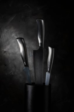 Bulanık duvarda üç metal bıçak.