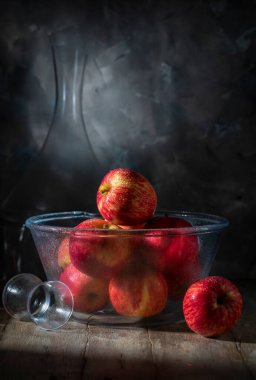 Ahşap masada kırmızı elmalı cam kase.