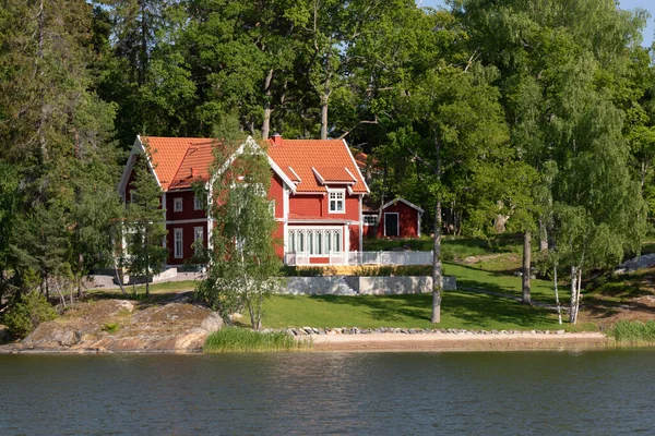 Beautiful red wooden house by the lake on a summer day