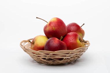 Beyaz arka planda hasır bir plakada kırmızı ıslak elmalar.