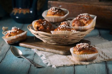 Mavi bir kırsal masada saman hasır bir tabakta ev yapımı tarçın ruloları.