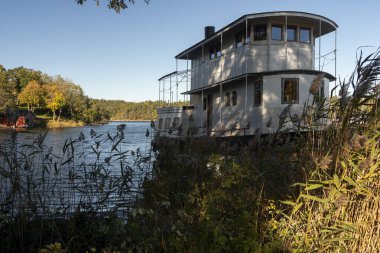 Güneşli bir sonbahar sabahında, fazla büyümüş bir göl kıyısında eski bir gemi.