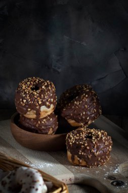 Gri bir duvara karşı tahta bir tahtanın üzerinde çikolata kaplı çörekler.