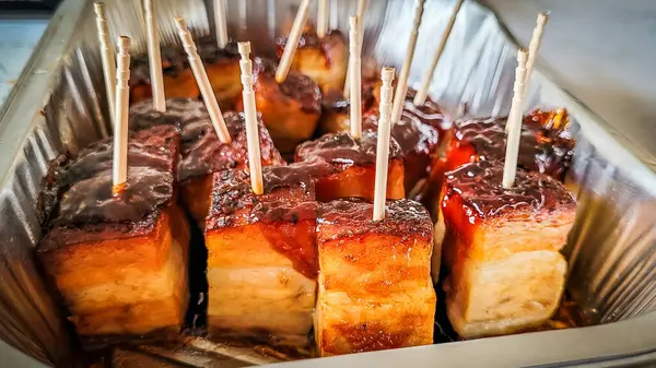 stock image Baked bacon pieces cut into cubes in a foil baking tray