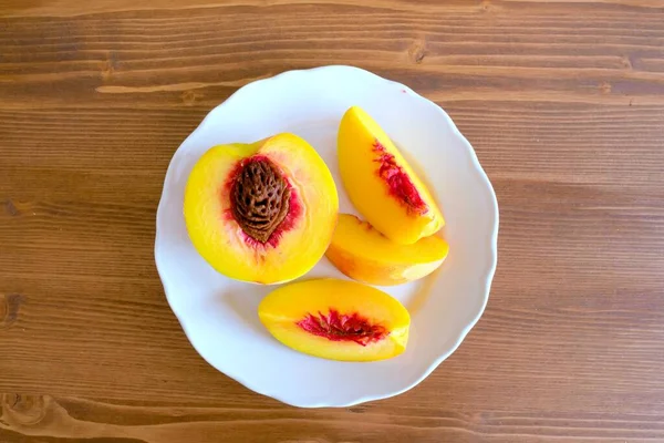 Sliced peaches on plate on wooden table