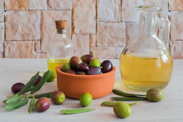 Background of unripe green olives and olive oil in a wooden plate