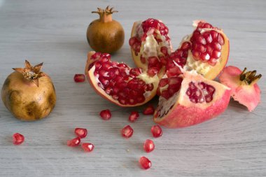 Tahta bir masada beyaz bir zemin üzerinde bir bıçakla taze, olgun bir nar.