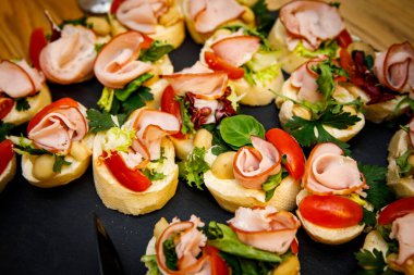 Siyah taş tabaklar üzerinde güzel küçük sandviçler. Büfe masası. Yemek servisi..