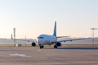 Uzun bir otoparktaki yolcu uçağı küçük bir havaalanında, sabah vakti.