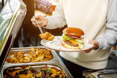 Otelde açık büfe kahvaltı. Tabakta bir hamburgerle misafir