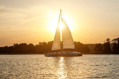 The yacht sails on the lake at sunset