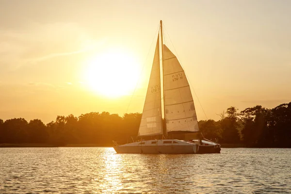 The yacht sails on the lake at sunset