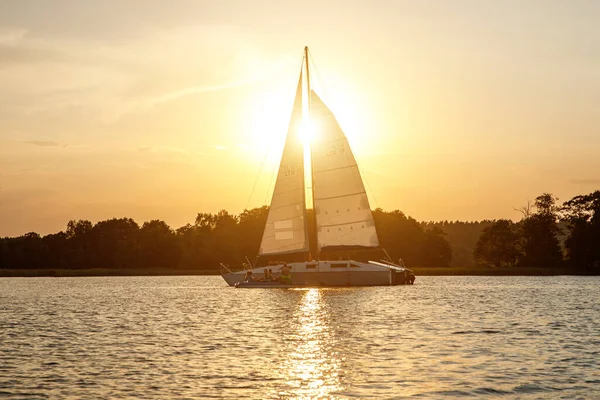 The yacht sails on the lake at sunset