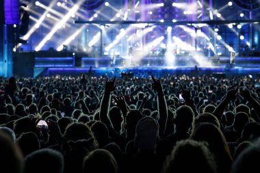 Konser salonundaki mutlu kalabalık. Kaldırılmış ellerin siluetleri