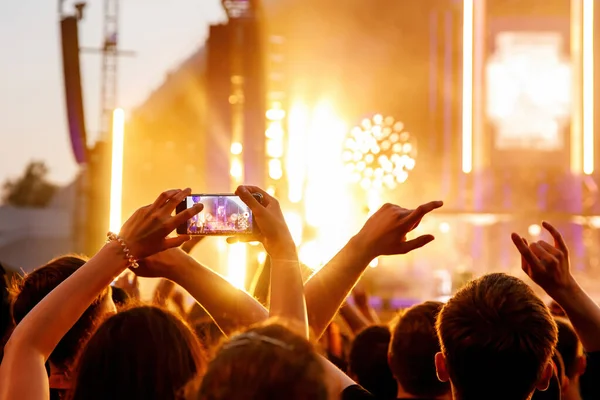Making video of concert using a smartphone. Cheering people on an amazing music show