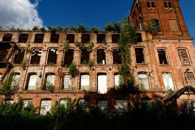 The building of an abandoned factory, red brick and broken glass in the windows