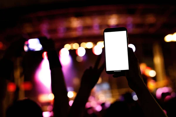 Using a mobile phone at a music concert. Mock-up with a blank screen for your picture