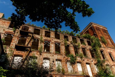 The building of an abandoned factory, red brick and broken glass in the windows