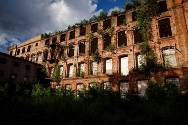 The building of an abandoned factory, red brick and broken glass in the windows