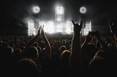 Silhouette of many people in a concert hall. Raised hands during a music show