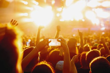 People with mobile phones record a music concert