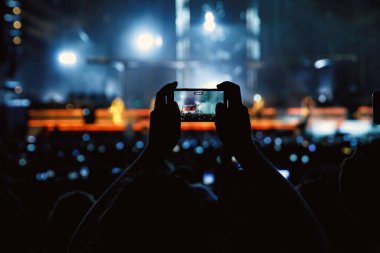 People with mobile phones record a music concert