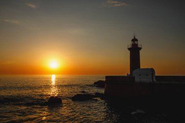 Gün batımında eski bir deniz fenerinin silueti