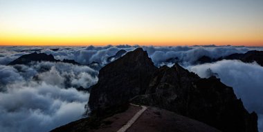 Gün batımında dağ zirveleri. Zirvenin altındaki bulutlar
