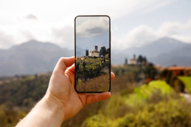 Seyahat fotoğrafçılığı: Turist akıllı telefon kullanarak güzel İtalyan manzarasının fotoğrafını çeker