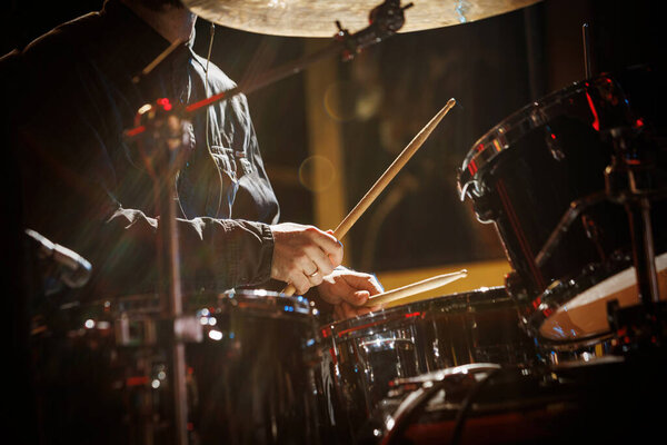 The drummer plays with drumsticks on the rock drum set.