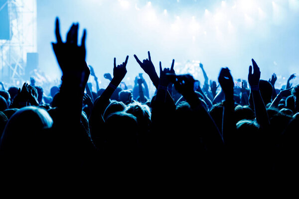 People with raised hands at a music concert. Fans in a concert hall