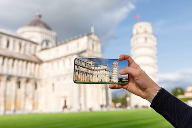 Seyahat fotoğrafçılığı: Turist ünlü Eğik Pisa Kulesi 'nin cep telefonuyla fotoğrafını çekiyor.