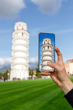 Seyahat fotoğrafçılığı: Turist ünlü Eğik Pisa Kulesi 'nin cep telefonuyla fotoğrafını çekiyor.