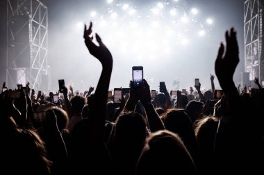 People with raised hands at a music concert. Fans in a concert hall