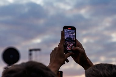 Kalabalık açık hava müzik festivalinin tadını çıkarıyor ve akıllı telefonlardan fotoğraf çekiyor.
