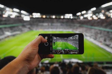 Stadyumdaki futbol maçını fotoğraflayan akıllı telefon.