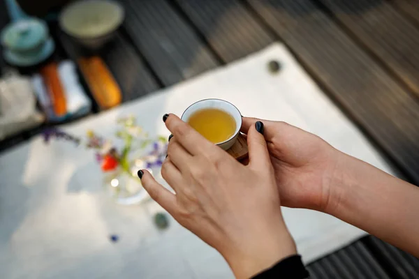 Tiny Chinese teacup in woman\'s hands during a tea ceremony