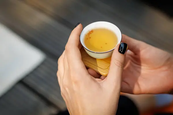 Tiny Chinese teacup in woman's hands during a tea ceremony
