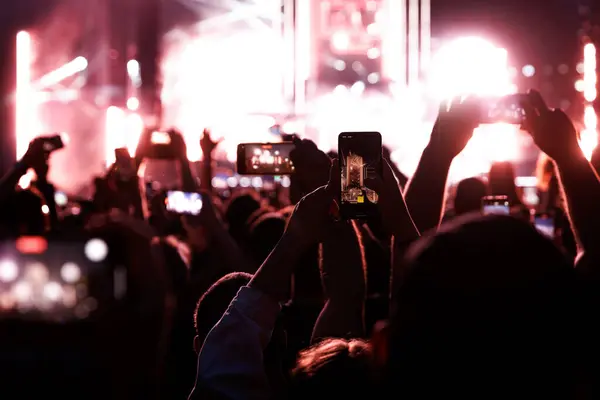 Crowd at a music festival. They are recording the show with their smartphones camera