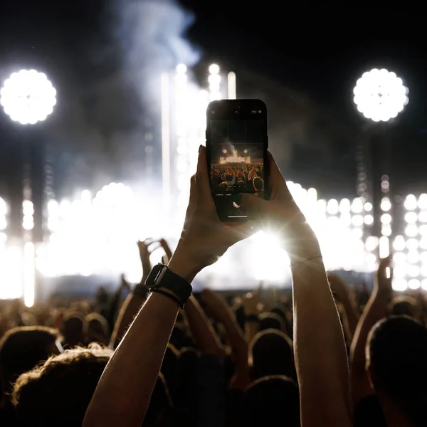 Silhouette of a hand with a mobile phone camera and enjoying the concert.