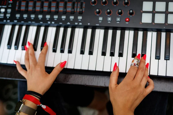 Top view of Red Nails Hands of a Pianist or Keyboardist from a Rock Band Playing a Synthesizer
