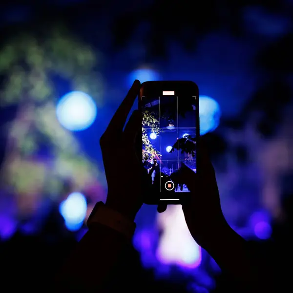 Silhouette of hand with smartphone at a music concert