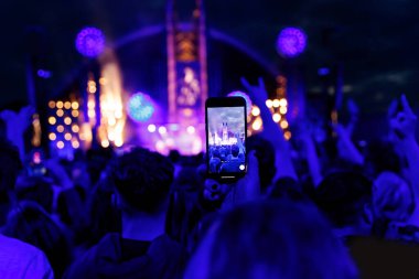 Konserde insanlar cep telefonlarıyla video veya fotoğraf çekiyorlar..