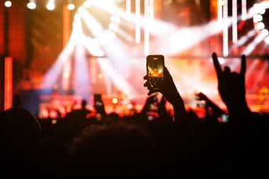 Konserde insanlar cep telefonlarıyla video veya fotoğraf çekiyorlar..