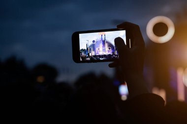 Konserde insanlar cep telefonlarıyla video veya fotoğraf çekiyorlar..