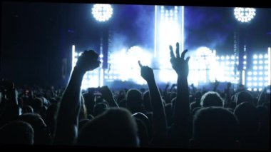 Konserde elleri havada bir kalabalık vardı. Sahne parlak ışıklarla aydınlanıyor.