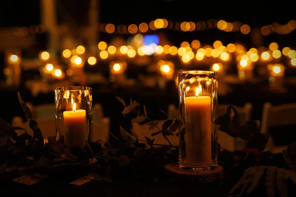 Gece etkinliğinde mum ve yeşillik yakılan romantik bir masa. Mumlar sıcak ve samimi bir atmosfer yaratırken, yeşillik ortama biraz zarafet katıyor..