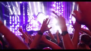 Performance of a popular group. The crowd with raised hands against the stage light